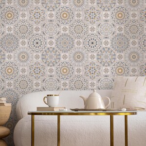 May include: A white sofa with a gold metal coffee table in front of it. The wall behind the sofa is covered in patterned wallpaper with a geometric design in shades of beige, brown, and blue.