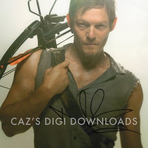 May include: A man with short brown hair is wearing a grey tank top and carrying a crossbow on his shoulder. He is looking at the camera with a serious expression. The crossbow is black with an orange arrow. The man's signature is visible in the lower right corner of the image. The signature reads "CAZ'S DIGI DOWNLOADS".