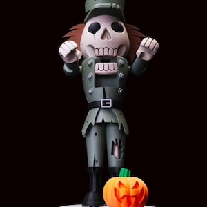 May include: A skeleton nutcracker figure wearing a muted green military-style uniform with a matching cap. The figure has a skull head, raised arms, and tattered clothing details. An orange jack-o'-lantern sits at its feet on a circular base.