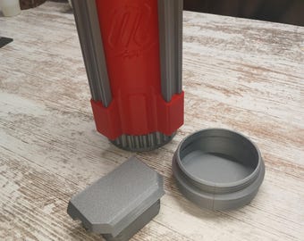 May include: A red and gray insulated can cooler with a matching lid and a separate gray bottom piece. The cooler has a logo on the side and is designed to keep beverages cold. The pieces are made of plastic.