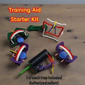 May include: A Training Aid Starter Kit with multiple colorful training devices. The kit includes various shapes and designs, with red, white, blue, green, and purple elements. The text "1 of each trap included" is visible.