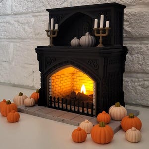 May include: A black fireplace with a lit fire and a shelf above with candles and small white pumpkins. There are several small orange and white pumpkins on the floor in front of the fireplace.