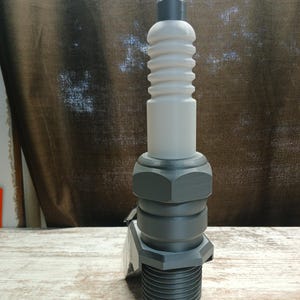 Op de afbeelding: Een grijze en witte flesstopper in de vorm van een bougie. De stopper heeft een schroefdraadbasis en een geribbelde bovenkant.