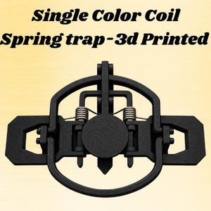 Peut inclure: Un piège à ressort à bobine noir imprimé en 3D avec une plaque circulaire centrale, un cadre ovale environnant et deux ressorts métalliques argentés. Le texte 'Single Color Coil Spring trap-3d Printed' est affiché au-dessus de l'objet.