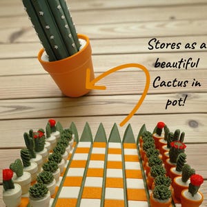 Może przedstawiać: Unikalny zestaw szachów Cacti z zielono-pomarańczową kolorystyką. Figury szachowe to miniaturowe kaktusy w białych i pomarańczowych doniczkach, ułożone na zielono-pomarańczowej szachownicy. Zestaw zawiera duży kaktus w pomarańczowej doniczce. Tekst na zdjęciu brzmi "Cacti Chess".