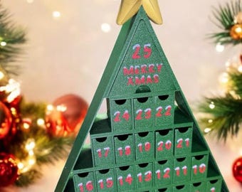 Könnte beinhalten: Ein grüner Adventskalender in Form eines Weihnachtsbaums mit 25 Schubladen. Die Schubladen sind von 1 bis 25 nummeriert. Die Spitze des Baumes hat einen goldenen Stern und den Text "25 MERRY XMAS".