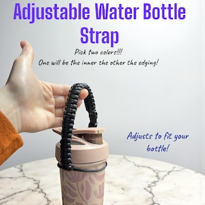 Può includere: Cinturino nero regolabile per bottiglia d'acqua. Il cinturino è attaccato a una bottiglia d'acqua con motivo floreale. Il testo dell'immagine recita "Cinturino regolabile per bottiglia d'acqua". Il cinturino si adatta alla tua bottiglia.