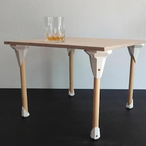 Pode incluir: Uma pequena mesa de madeira com tampo de madeira clara e pernas brancas. A mesa tem um design simples e é perfeita para um espaço pequeno.