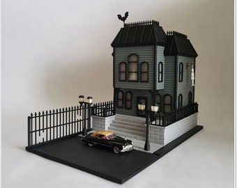 May include: A black and grey model house with a black fence and a black car in front of it. The house has a black roof and a bat on top. The car is a classic model with a yellow interior.