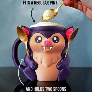 May include: A novelty purple bat-shaped mug with a pink nose and large eyes, holding two gold spoons. The mug is filled with ice cream, and a spoon is scooping more ice cream into the mug. Text on the image reads: FITS A REGULAR PINT and AND HOLDS TWO SPOONS.