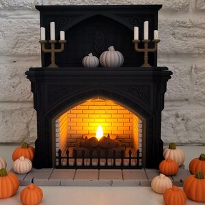 Puede incluir: Una chimenea negra con una chimenea encendida y dos juegos de candelabros con velas blancas. La chimenea est&aacute; decorada con tres calabazas blancas y rodeada de calabazas naranjas y blancas.