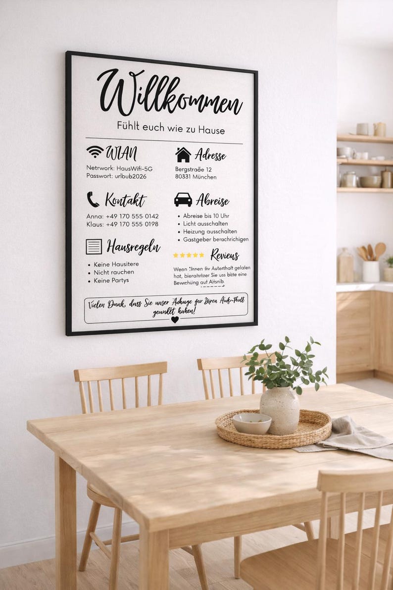 May include: A framed sign with German text, including "Willkommen" and house rules, hangs above a wooden table set for dining. The sign provides Wi-Fi details and contact information. A vase with greenery sits on the table.