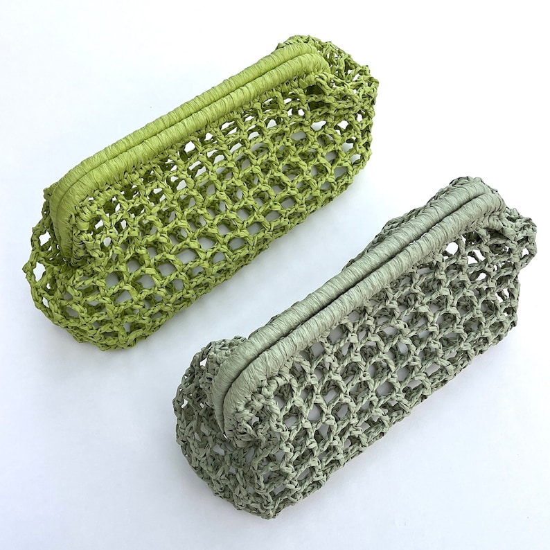 May include: Two rectangular clutch bags featuring an open-weave net construction. One bag is a vibrant lime green, while the other is a muted sage green. Both clutches have a structured, wrapped top frame closure and a consistent grid pattern.