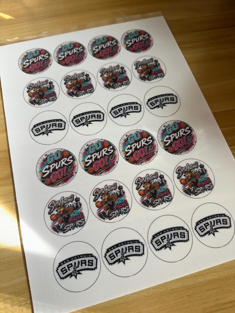 May include: A sheet of circular stickers featuring San Antonio Spurs basketball designs. The stickers include text such as Go Spurs Go, San Antonio Spurs, and Puro Pinche Spurs, alongside illustrations of a basketball-playing coyote mascot.