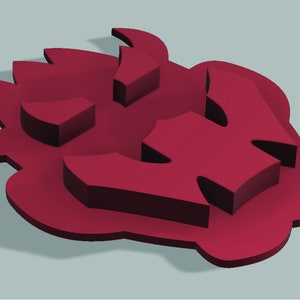 Puede incluir: Un dise&ntilde;o de pl&aacute;stico rojo impreso en 3D de una cara estilizada con cuernos y un dise&ntilde;o en forma de llama.
