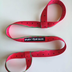 May include: Red and green watermelon-patterned wrist strap with the text "ENJOY YOUR SKATE" in black.