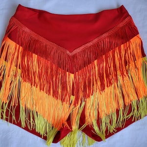 May include: Red shorts with yellow and orange fringe trim. The fringe is layered and creates a dramatic look.