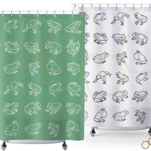 May include: Two shower curtains with a white frog pattern on a green and white background. The shower curtains are hung on a shower rod.