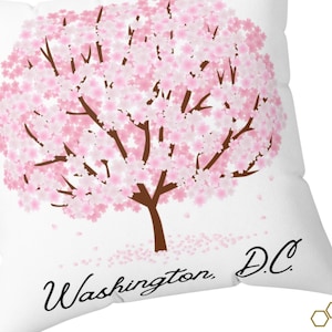 May include: White pillow featuring a pink cherry blossom tree illustration and the text "Washington, D.C."