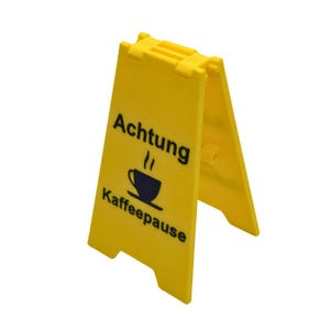 Könnte beinhalten: Ein gelbes Schild aus Kunststoff mit schwarzem Text, der "Achtung Kaffeepause" lautet, und einer schwarzen Silhouette einer Kaffeetasse mit Dampf, der aus ihr aufsteigt.