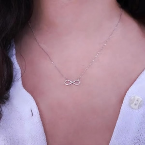 Pode incluir: Um colar de infinito de prata com pequenos diamantes cravejados no símbolo do infinito.