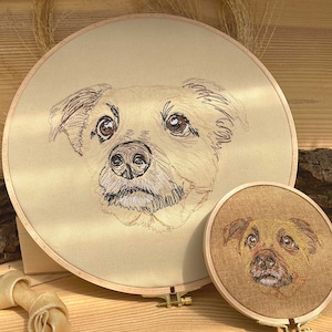 May include: Two embroidered portraits of dogs on circular fabric stretched over wooden hoops. The larger hoop features a light brown dog with a white muzzle, while the smaller hoop features a brown dog with a white muzzle.