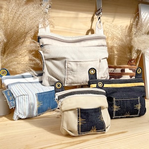 Può includere: Cinque borse di tessuto diverse con chiusure a zip. Le borse sono realizzate in tessuto a righe, denim e tela. Le borse sono di diverse dimensioni e forme.