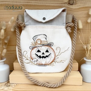 Może przedstawiać: Kremowa torba na ramię z motywem Halloween, z klapką i paskiem z liny. Torba posiada haftowaną dynię w kapeluszu z motywem zegara. Torba ma pasiastą klapę i zapięcie na guzik.