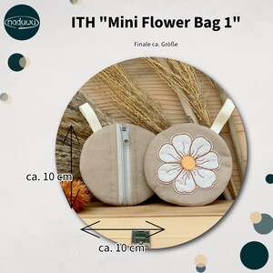 May include: Two beige, round mini flower bags, each approximately 4 inches in diameter, are displayed. One bag has a zipper, and the other features a white flower with an orange center. The bags have a cream-colored loop and the text "ITH Mini Flower Bag 1".