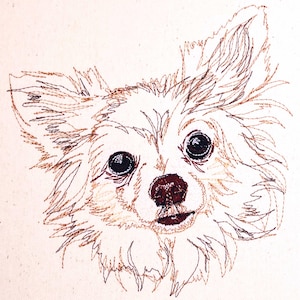 May include: A close-up of a brown and white embroidered image of a chihuahua dog with its head tilted to the side. The dog has brown eyes and a brown nose.