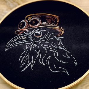 Könnte beinhalten: Gestickte Darstellung eines Rabens mit einem Steampunk-Hut mit Schutzbrille auf einem schwarzen Stoffhintergrund.