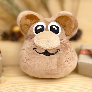 May include: A brown plush toy mouse with large eyes and a smiling mouth. The mouse has a brown nose and whiskers.