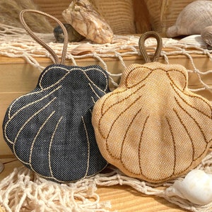 Pode incluir: Duas bolsas de tecido em forma de concha com al&ccedil;as para pendurar. Uma bolsa &eacute; feita de tecido jeans azul escuro com costuras claras, e a outra &eacute; feita de tecido bege com costuras escuras. Ambas apresentam um design de borda festonada.