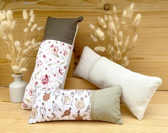 Peut inclure: Plusieurs coussins décoratifs rectangulaires. L'un présente un motif floral, un autre des illustrations de poulets, et le troisième est uni. Les coussins ont des accents marron ou beige. Le texte "In The Hoop - Outside The Hoop" est en bas de l'image.