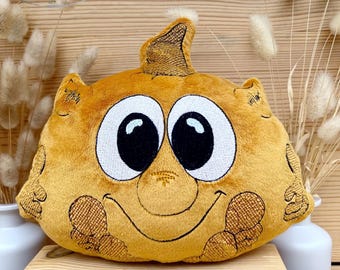 Puede incluir: Un cojín de felpa amarillo mostaza con forma de personaje de dibujos animados, con ojos grandes con borde blanco y una cara sonriente. El cojín tiene una superficie texturizada y un pequeño elemento puntiagudo en la cabeza. La marca "naduuu" es visible.