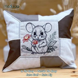 May include: Square patchwork pillow featuring an embroidered mouse holding red flowers. The pillow has a gray, brown, and white striped pattern. The text "In The Hoop - Outside The Hoop Extra Groß - Extra Big" is at the bottom.