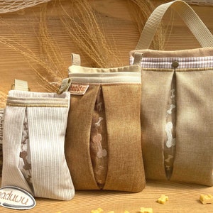 Op de afbeelding: Drie beige stoffen hondensnoepzakjes met een bruin en wit gestreept patroon. De zakjes hebben een klep met een botontwerp en het woord "Lohnstufe" erop gedrukt. De zakjes hebben een band om te dragen.