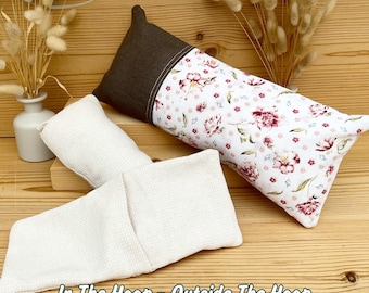 Peut inclure: Deux oreillers et une enveloppe pliée sont présentés sur une surface en bois. Un oreiller est blanc avec un motif floral, l'autre est blanc avec un tissage texturé. Le troisième article est une enveloppe blanche pliée. Le texte "In The Hoop - Outside The Hoop" est visible.