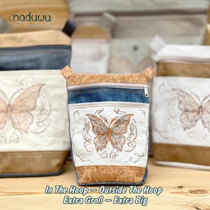 Könnte beinhalten: Kleine, rechteckige Tasche mit Schmetterlingsstickerei. Sie hat einen Korkboden, einen Jeans-Oberteil und ein weißes Stoffpaneel mit detailliertem Schmetterlingsdesign. Der Text "In The Hoop - Outside The Hoop Extra Big" ist sichtbar.