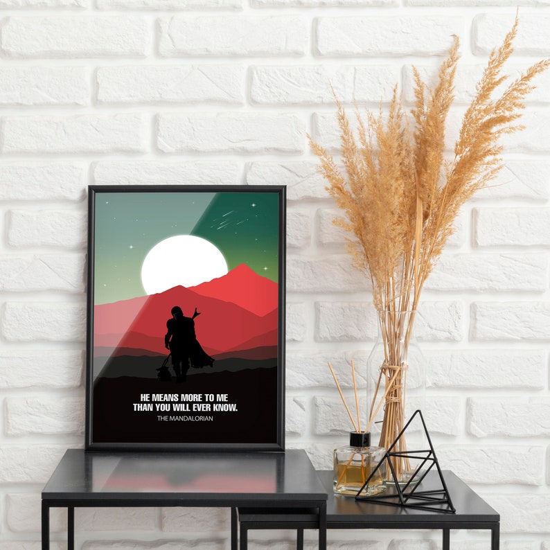 May include: A black framed poster with a green, red, and white landscape scene. The poster features a silhouette of a person walking with a small creature. The text on the poster reads "He means more to me than you will ever know. The Mandalorian."