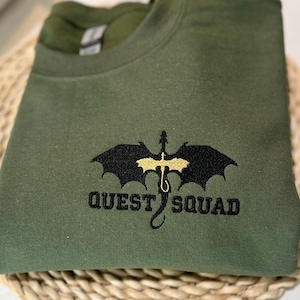 May include: A green sweatshirt with a black dragon and the text "QUEST SQUAD" embroidered in gold thread.
