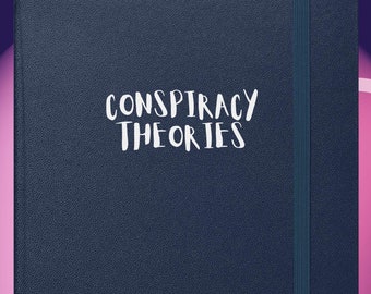 May include: A navy blue notebook with the words "CONSPIRACY THEORIES" in white script. The notebook has an elastic band closure and a textured cover. The background features a purple and pink gradient.