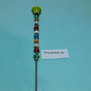 May include: A silver threaded rod with a green ceramic top and colorful beads. The beads are red, white, green, blue, orange, and yellow. The rod is labeled "Threaded Rod #3".