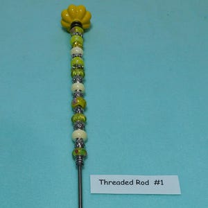 May include: A yellow and white beaded threaded rod with a yellow flower-shaped top. The rod is labeled "Threaded Rod #1".