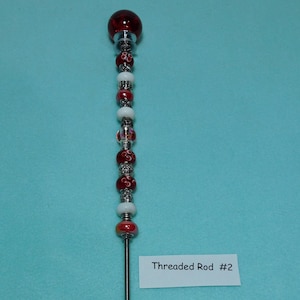 May include: A silver threaded rod with a red glass bead at the top and a variety of red, white, and silver beads along the length. The rod is labeled "Threaded Rod #2".