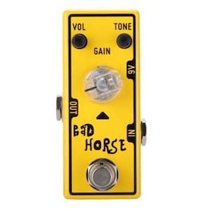 Puede incluir: Pedal de guitarra amarillo con el texto "Bad Horse" y perillas etiquetadas como "Vol", "Tone" y "Gain".