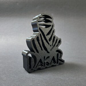 Side view of a 3D printed black DAKAR logo stand