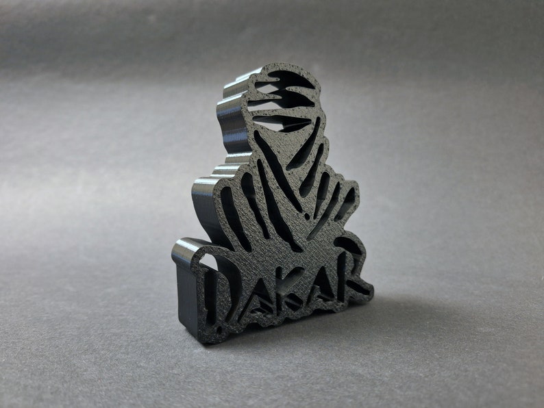 Side view of a 3D printed black DAKAR logo stand