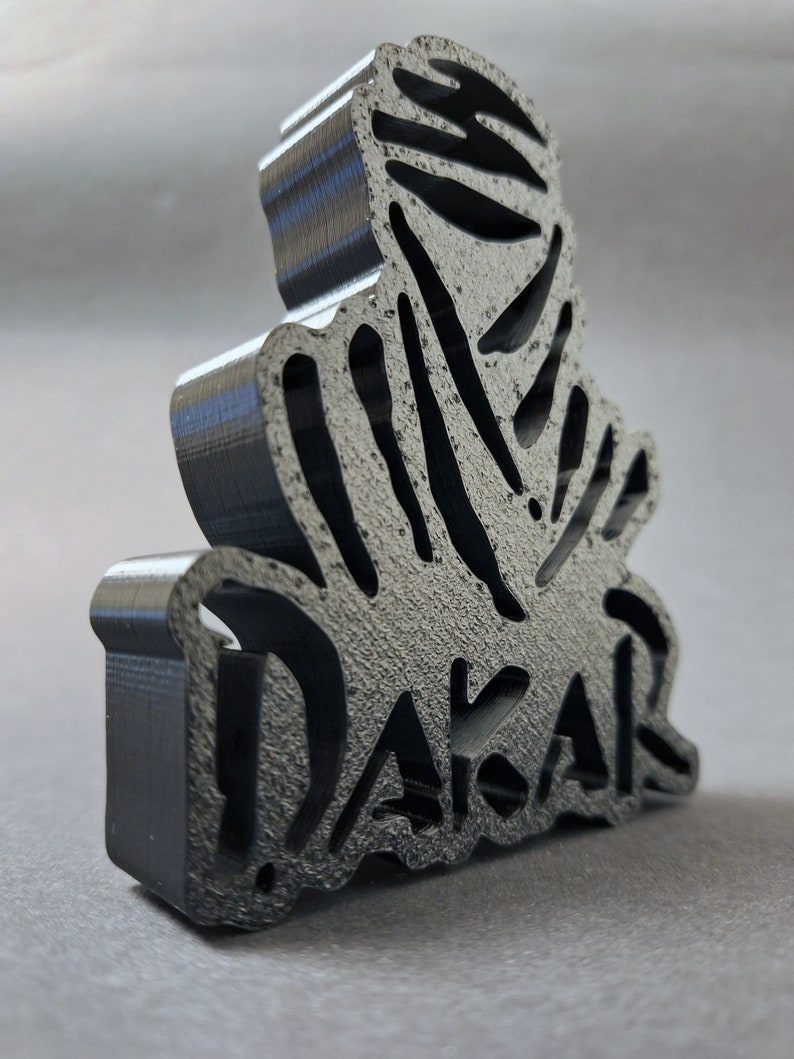 Side view of a 3D printed black DAKAR logo stand