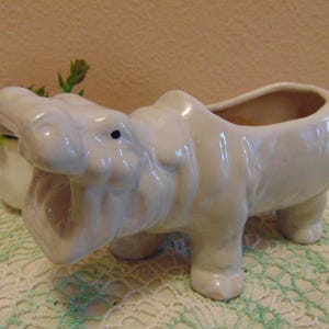 May include: A set of three ceramic nesting bowls in graduating sizes. The bowls are white with a speckled, textured finish and a slightly flared rim. The largest bowl measures approximately 8 inches in diameter.
